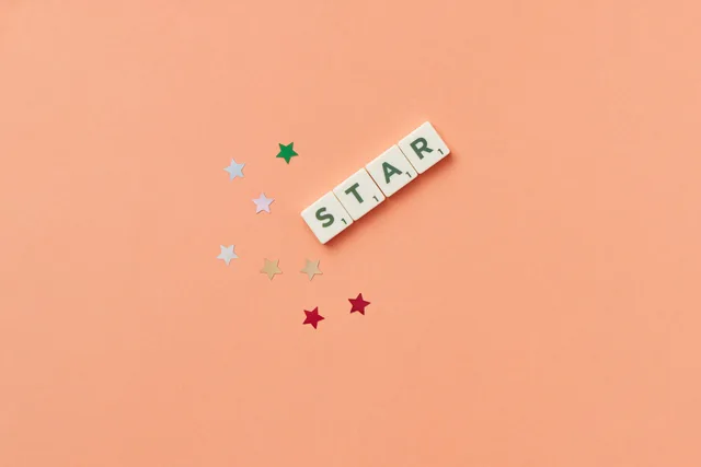 Flat lay image of Scrabble letters spelling 'STAR' on a peach background with colorful stars. Commerce reviews disclosure policy explained for England