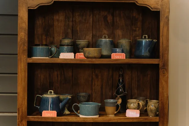 Artisan pottery cups and teapots on a wooden shelf, highlighted with sale tags. Commerce reviews measurement without vanity metrics